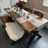 Rustic wooden dining table set with black metal x-frame legs and red roses in glass vase free home delivery available