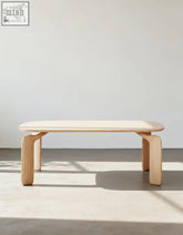 Minimalist light wood domingo dining table with smooth rounded top and sleek curved legs in sintered stone finish