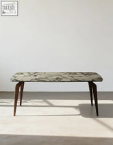 A sleek dominic dining table with a polished green and white marble top and dark wood legs perfect for dining areas