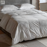 A plush off-white quilted duvet with duck feather and down filling soft textured fabric and subtle stitching details