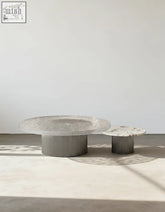 Two minimalist eirik coffee tables with circular white marble tops and transparent acrylic grooved bases, one larger than the other