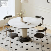 Elmer round dining table with white marble effect top and pedestal base surrounded by four black upholstered chairs