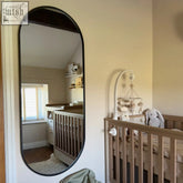 Black oval emi 150x60cm full length metal runway mirror with matte black frame reflecting nursery interior