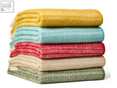 Stack of five fair isle pure new wool throws in vibrant yellow teal red beige and green with textured zigzag pattern