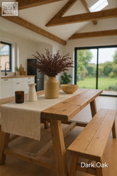 Dark oak farmhouse dining table with natural grain finish and matching bench shown in bright kitchen with table length focus