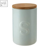 A fenwick pale blue sugar canister made of matte light green ceramic with a natural wood lid and embossed s on the side