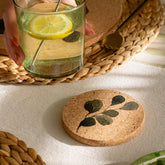 Round cork coaster with dark green leaf design made from heat resistant portuguese cork for protecting surfaces