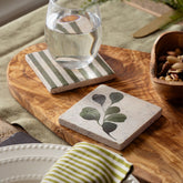 Two square flora single stone coasters with green leaf design and olive stripes made of heat resistant natural limestone