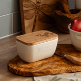 Cream-colored ceramic butter dish with natural wood lid and engraved floral design for kitchen use