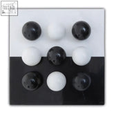 Flos black and white tic tac toe marble game with black and white spherical pieces on a split black and white surface