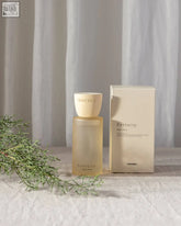 A sleek translucent amber glass fortuity clay home spray bottle with a matte cream cap beside its matching box