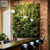 Lush green living wall with diverse leafy plants on brick featuring frameless plant cassette table system