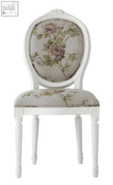 A white upholstered french oval back chair with a floral pattern in muted rose and green tones