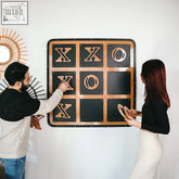 A modern wall-mounted giant xox board tic tac toe game with black surface and copper xs and os
