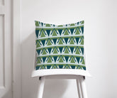 A green and grey art deco throw pillow with eye catching geometric triangles on a white chair
