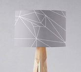 Gray table lamp shade with white line geometric design on light wood tripod base with inch diameter size