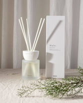 White ceramic halo clay reed diffuser with frosted glass base and six slender reed sticks for home fragrance