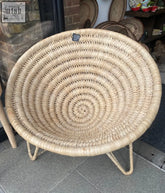 Beige handwoven cone chair made of rattan with a spiral pattern and thin metal legs from mozambique