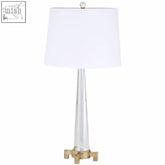 A hania table lamp with a sleek clear glass base and gold toned metal accents for modern lighting