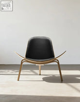 Black leather seat with curved walnut frame and legs on hans wegner ch07 shell chair in black and walnut
