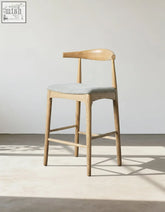 Light wood hans wegner ch32 bar stool with gray linen upholstered seat and curved backrest in oak and rosewood