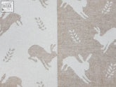 Hare merino lambswool throw in fawn with leaping rabbits and leaf pattern in muted beige gray and off-white tones