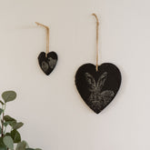 Black heart-shaped slate heart decoration with engraved rabbit and bird designs hanging by natural twine