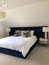 Navy blue upholstered bed with white bedding and decorative pillows featuring the harewood headboard design
