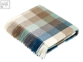 A soft harlequin check lambswool throw in beige blue and green plaid made from cozy merino lambswool with fringed edges