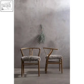 Two minimalist y-shaped dining chairs with natural oak wood frame and grey fur dining seat cushions