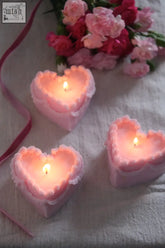 Three pink heart cake candles with ruffled edges and lit wicks perfect for romantic cake decoration