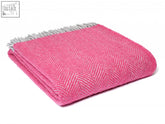 A vibrant pink herringbone pure new wool throw with a contrasting gray fringe perfect for cozying up