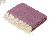 A soft lavender pink herringbone shetland wool throw with cream-colored fringe perfect for cozying up