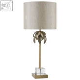 Herta antique brass palm tree design table lamp with gold-toned leaf, beige drum shade, and clear crystal base