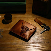 Brown genuine leather wallet with detailed black engraved highland cow design on the front