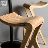 Light-colored hina bar stool with sleek curved wooden seat and x-shaped legs in japanese design style