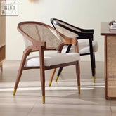 Modern hinata chair with curved wooden frame, woven cane back and seat, white upholstery, dark legs with gold tips