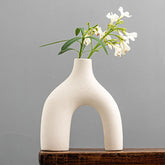 Cream-colored ceramic hiroki vase with unique arch-shaped design holding delicate white flowers