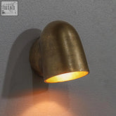 A warm-toned solid cast brass mast down light wall sconce with a curved industrial design in antique brass finish