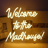 A glowing yellow led neon sign saying welcome to the madhouse perfect for bedroom bar or club wall decor