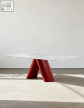 A sleek hossain dining table with a marble top and bold glossy red v-shaped legs perfect for marble dining rooms