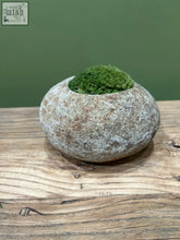 A smooth indo riverstone planter with a weathered gray brown surface planted with vibrant preserved moss