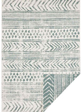A reversible geometric indoor-outdoor area rug with teal and off-white chevrons diamonds and stripes pattern