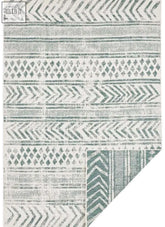 A reversible geometric indoor-outdoor area rug with teal and off-white chevrons diamonds and stripes pattern