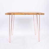 A rustic wooden industrial farmhouse desk with rose gold steel hairpin legs perfect for a stylish workspace