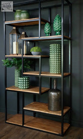 Industrial multi shelf unit with black metal frame and natural wood shelves displaying green ceramic art pieces