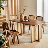 Warm-toned isla dining table with woven cane legs and side panels made of solid wood and rattan materials