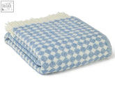 A soft jacquard spot wool throw blanket in blue jay with white checkered spot design and cream-colored fringe perfect for cozying up