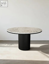 Jean round dining table with white marble top and black ribbed pedestal base perfect for modern round dining spaces