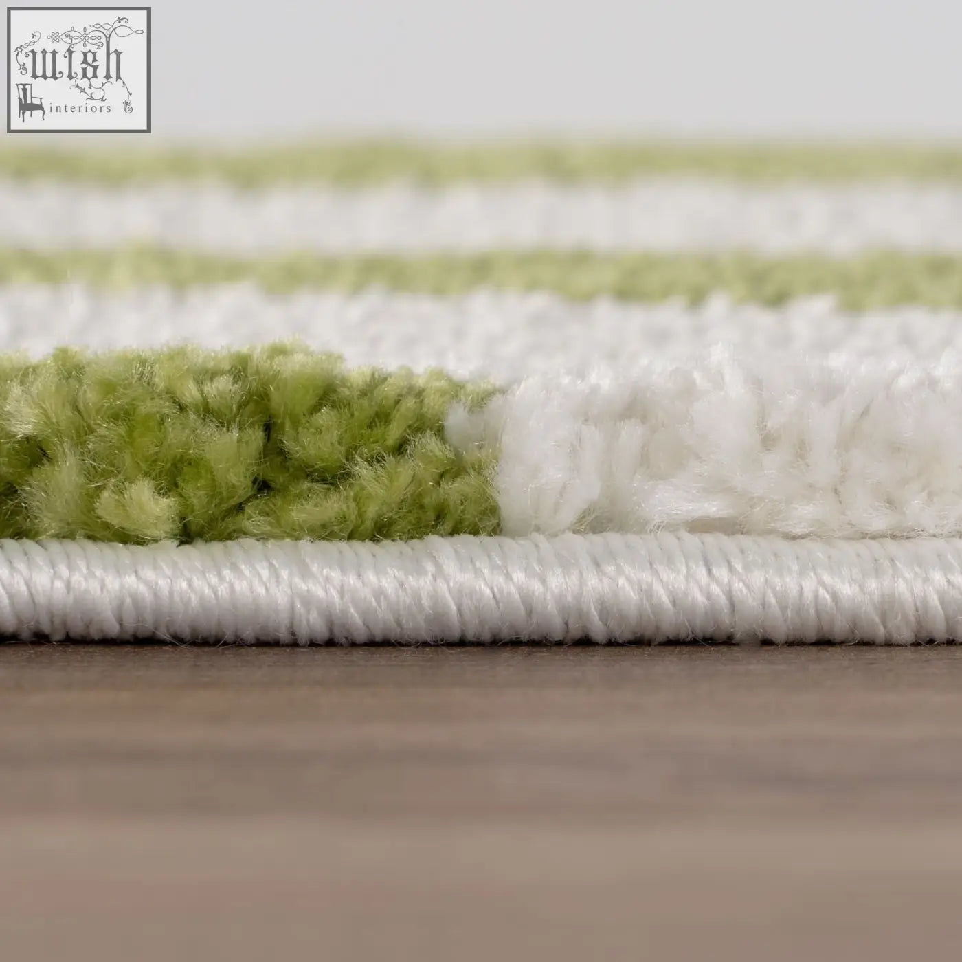 A joli doodle green plush rug with soft white and light green stripes and a neatly bound white edge